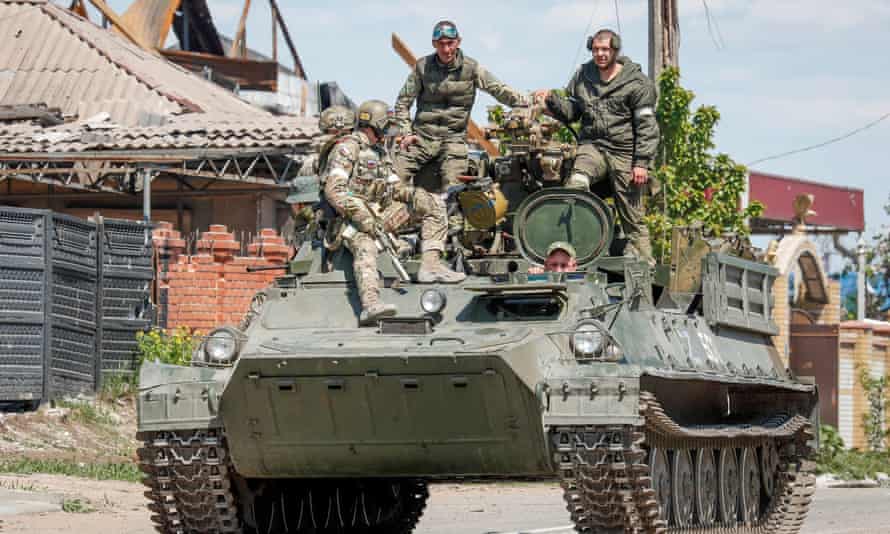 Russian service members are seen atop of an armoured vehicle in the southern port city of Mariupol.