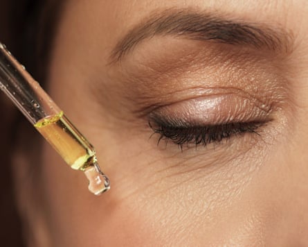 A closeup of a woman’s eye and a dropper with rejuvenating serum