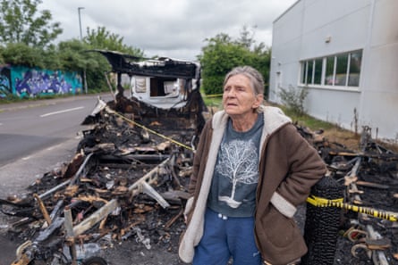 Johnston standing with burnt shell of vehicle behind