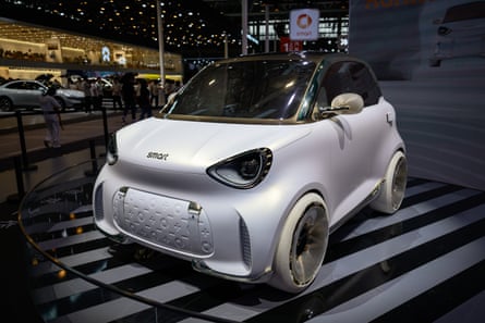 A pearly white two-seater car on a dais indoors