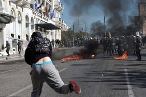 Greek police stand guard amid molotov cocktails thrown by protesters during a massive demonstration as part of a 24-hour general strike in Athens on November 12, 2015. Around 20,000 people demonstrated against fresh cuts in Athens, with sporadic outbreaks of violence, in the first general strike against the leftist government of Alexis Tspiras who swept to power on an anti-austerity ticket. AFP PHOTO / LOUISA GOULIAMAKILOUISA GOULIAMAKI/AFP/Getty Images