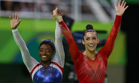 Simone Biles, left, and Aly Raisman wave to the crowd as they wait for Biles’ score after competing on the floor.