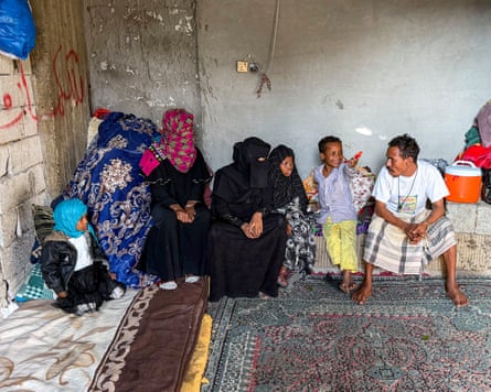 A man, two women and two small children sit in the corner of a room