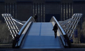 A man wearing a mask walking over the Millennium Bridge in London this morning.