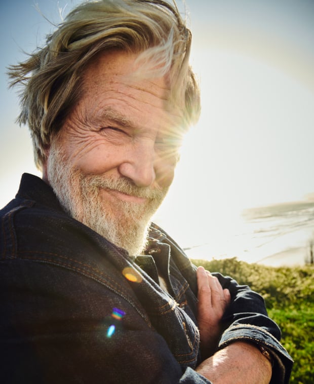 Jess Bridges with the sun and sky behind him, smiling with his arms folded