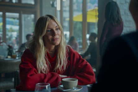 Miller in red top sits at a table with a coffee in front of her