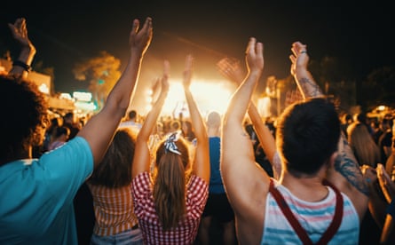 Closeup of group of young adults dancing and enjoying an open air concert on a summer night