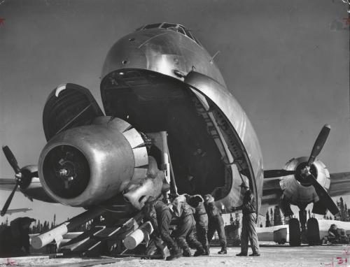 Crewmen unloading huge B-52 bomber engine used as spare, from the belly of a C-124 cargo plane upon arrival at Strategic Air Command’s advance base, 1951, Margaret Bourke-White