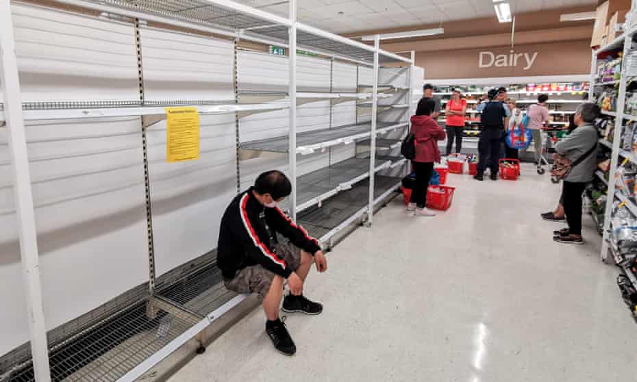 Supermarket customers wait for a delivery of toilet paper.