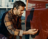 a man inspects a scratch on a red van