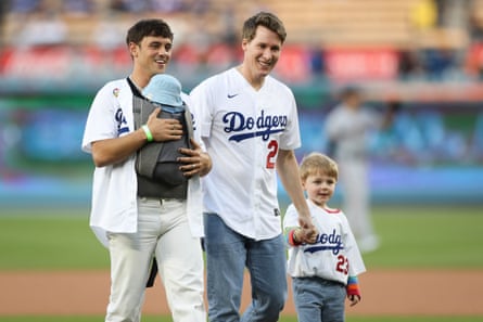 Tom Daley, carrying his baby son, and Dustin Lance Black, holding the hand of their older son, at a baseball game in LA