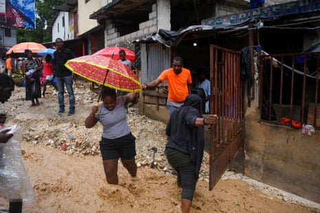 People cross a flooded street after heavy rains caused by the outer bands of Hurricane Melissa flooded some areas, in Port-au-Prince, Haiti, October 29, 2025.
