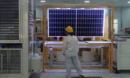 A worker conducts a quality check of a solar module product at a Longi factory in Xian, China