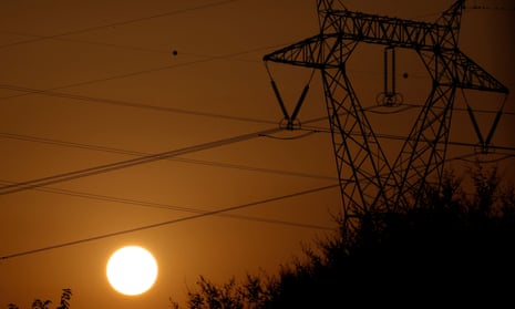 the sun behind electricity pylons