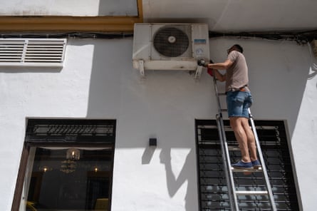 A technician repairs an air conditioning unit at a restaurant in the city centre of Ronda, southern Spain, on Sunday.