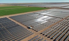 huge fields of solar panels next to a field of green crops