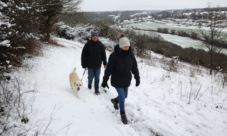 A couple walk their dog in the snow at Dartland Banks nature reserve near Hampstead, near Sevenoaks.