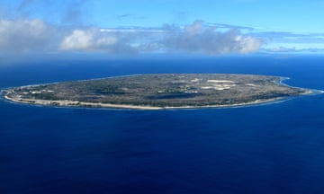 Nauru island from the air - Pacific Ocean<br>Nauru island: the entire country seen from above - Island surrounded by the coral reef - the oval island has a narrow coastal belt with vegetation where settlements are located, the interior is mostly barren terrain with jagged limestone pinnacles due to the environmental damage caused by phosphate mining - Yaren and the airport on the left - Pacific Ocean -  Pacific Community.