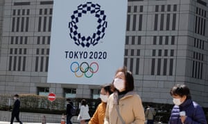 Peatones con mascarillas en el exterior del edificio del Gobierno Metropolitano de Tokio, que lleva el logotipo de los Juegos Olímpicos de 2020