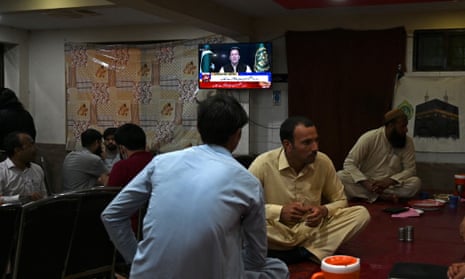 People listen to Imran Khan’s address to the nation at a restaurant in Islamabad