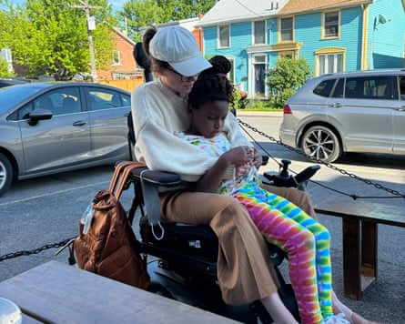 A woman on a wheelchair embracing a child.