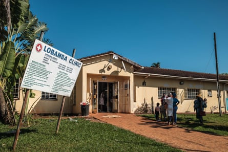 People stand outside a one-storey building with a sign for the clinic on a lawn