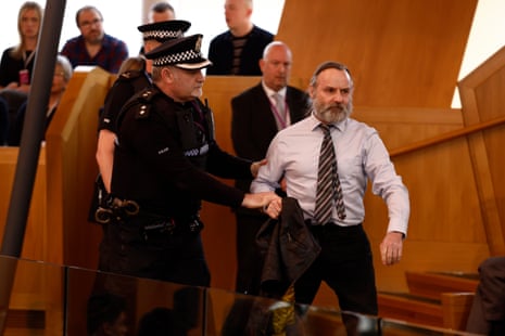 Police and security staff escort a protester from the public gallery during FMQs.