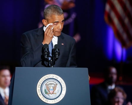 Barack Obama wipes his eyes as he stands behind a podium