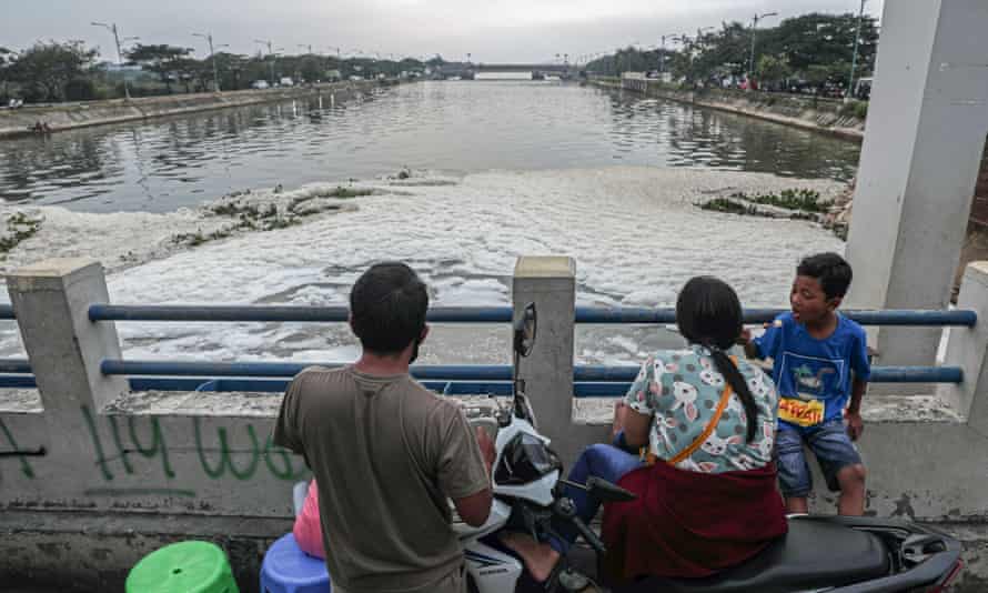 A family looks over the pollution spilling from the Marunda sluice bridge in Jakarta.