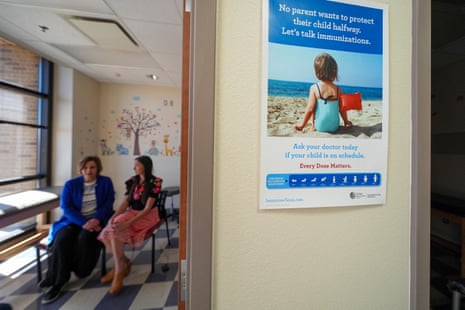 An immunization poster hangs by a doorway as Tammy Camp and Summer Davies talk inside an office