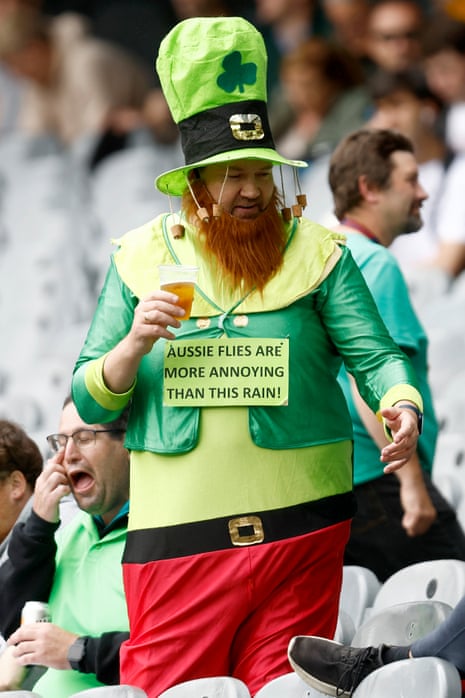 Ireland fan dressed as a leprechaun with  a sign saying Aussie flies are more annoying than this rain. 