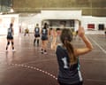 A volleyball player raises both hands behind teammates during a match on an indoor court