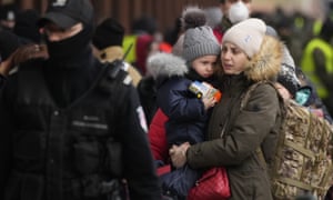 Μια γυναίκα κρατά ένα παιδί καθώς περπατά με άλλους, αφού αποβιβάστηκε από ένα τρένο με καταγωγή από το Lviv της Ουκρανίας, στον σταθμό στο Przemyśl της Πολωνίας.