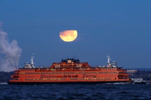 The glowing satellite sets as the Staten Island ferry, in Brooklyn, New York, moves into view