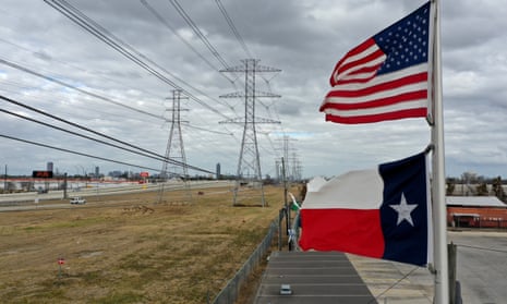 The US and Texas flags fly in front of high voltage transmission towers in Houston, Texas, on Sunday.