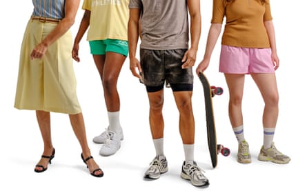 Four people wearing shorts. One has their top tucked in and another is holding a skateboard