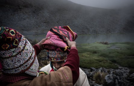At the foot of a snow-capped peak, a Quechua father and son in traditional dress perform the ancient ritual of spiritual purification and union with Pacha Mama