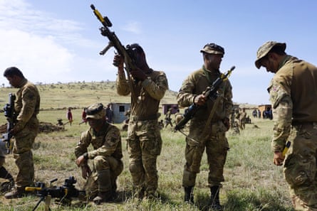 Soldiers disarm their weapons, one pointing rifle in the air