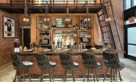 The Bugatti bar at the Archer hotel in New York City. Chairs are lined up in front of the bar, while around the exposed brick walls there are Bugatti posters.