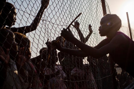 At the UN camp in Malakal, a girl hits children through a fence that divides the Nuer and Shiluk ethnic groups