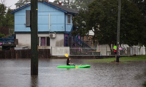 A child paddles a canoe in a flooded street in Windsor, NSW, on Monday morning