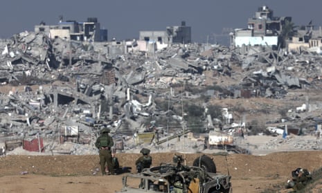 Israeli soldiers stand guard near the Israeli-Gaza border overlooking the Shujaiya neighbourhood near Gaza City