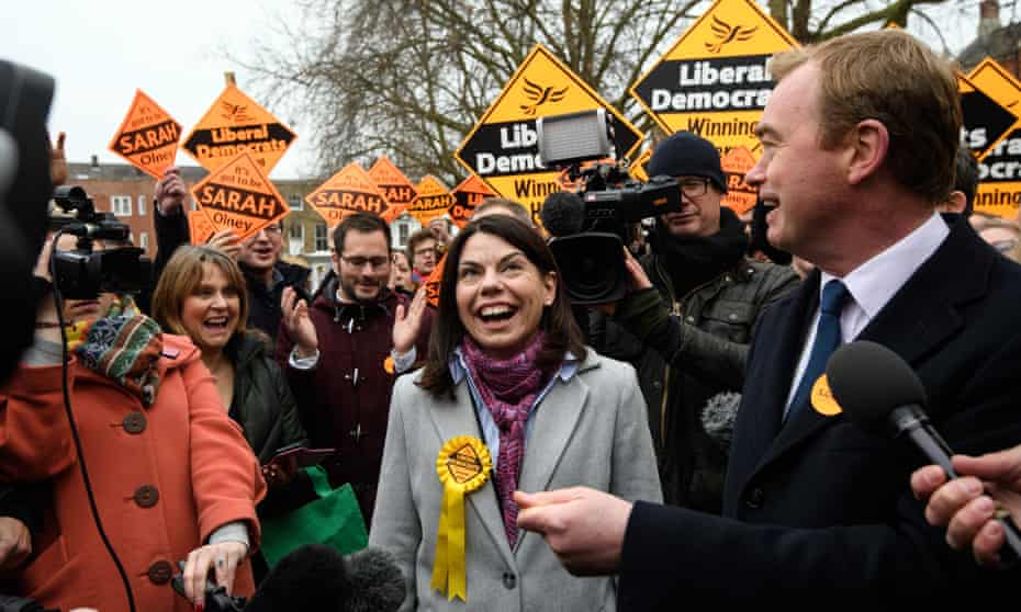 Sarah Olney and Tim Farron surrounded by members of the media