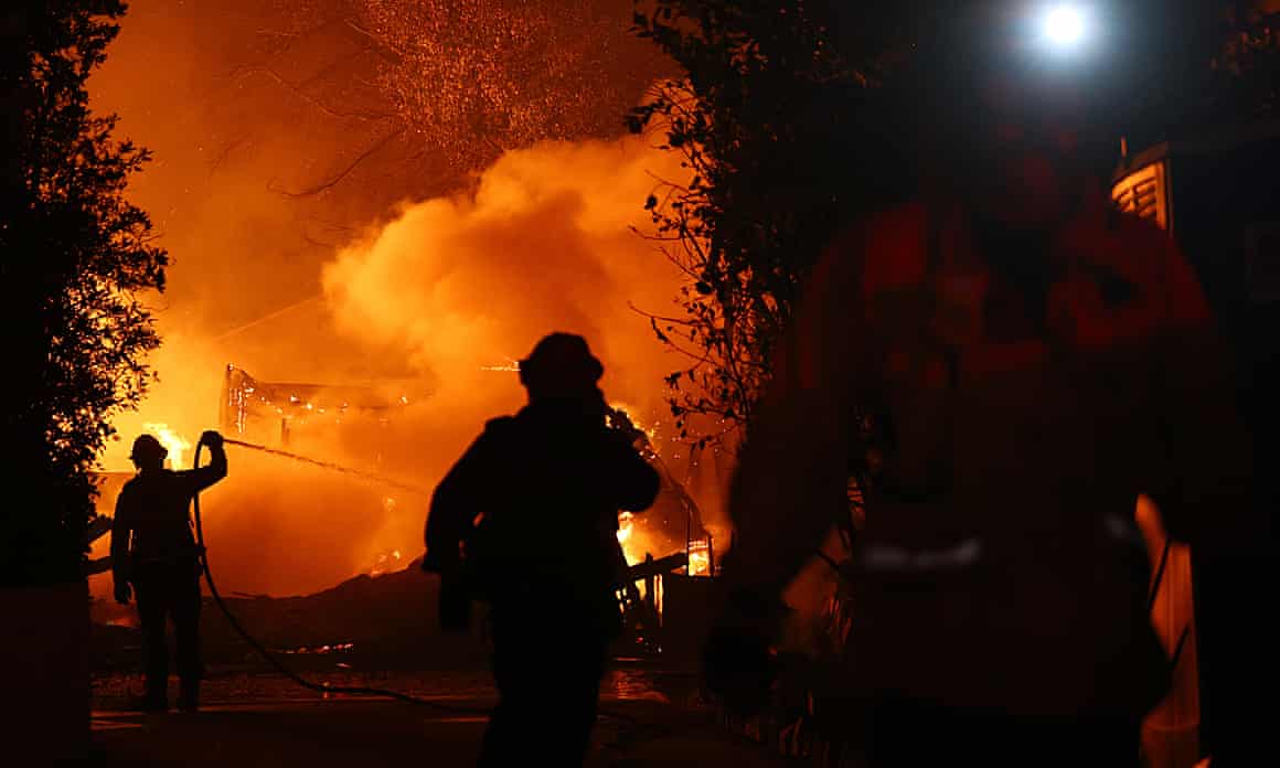 Firefighters work as a home burns during the Eaton Fire while a powerful windstorm impacts the region.