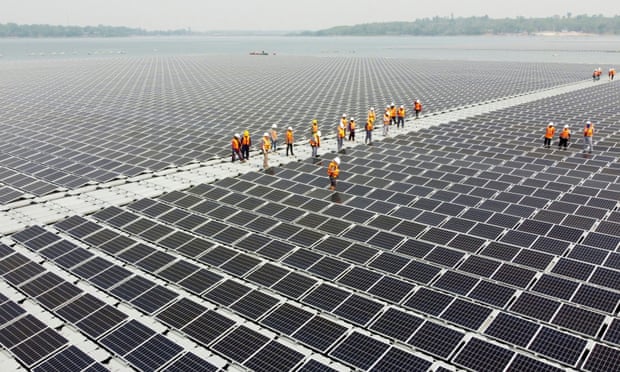 Workers walk between solar panels over the water surface of Sirindhorn Dam in Ubon Ratchathani, Thailand.
