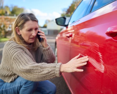 woman looks at scratches on her red car