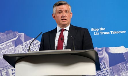 Jonathan Ashworth standing at a podium with a microphone