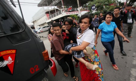 People carry an unconscious woman to an ambulance in front of a church after a would-be suicide bomber failed to detonate explosives during Sunday service in Medan.
