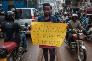 Leah Namugerwa, a 15-year-old climate activist, holds a placard in Kampala.