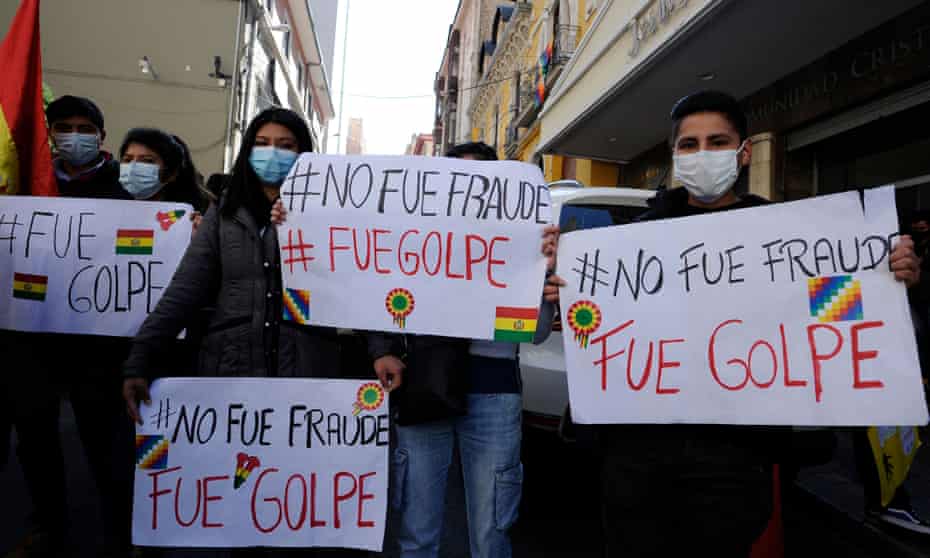 people hold signs at a demonstration against the former president Jeanine Áñez's government outside Bolivia's Central Bank Auditorium, in August